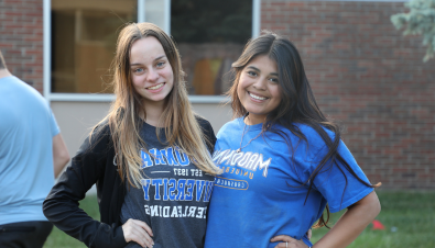 two students smile for the camera outside a madonna university building